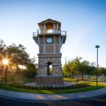 The Santa Fe College clock tower stands at the center of campus in Gainesville, FL, as the sun rises behind it.