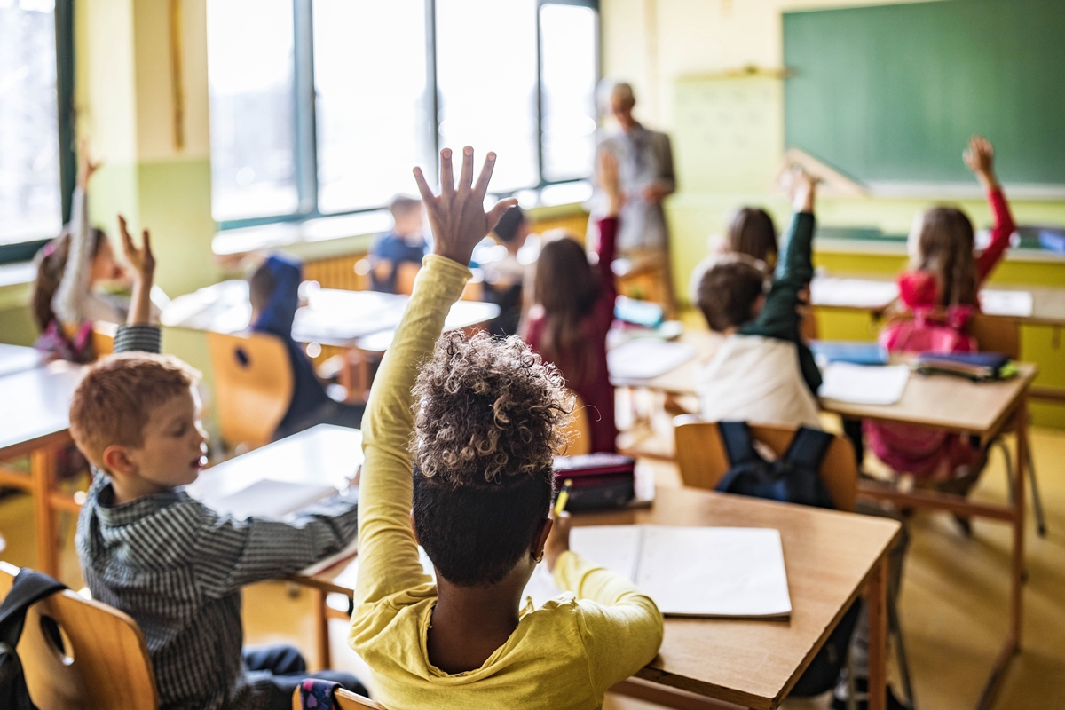 Students raise their hands during a classroom lesson at an elementary school.