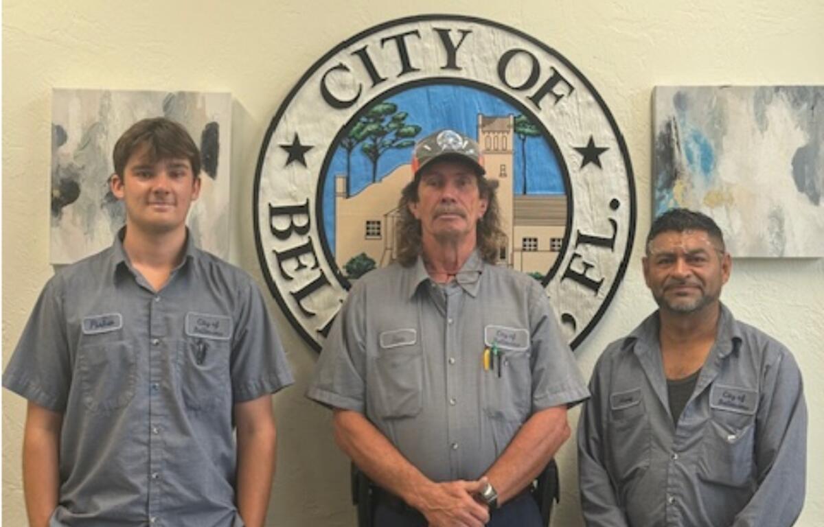 Three Belleview Public Works employees—Fisher Houston, Ronald Everett, and Henry Somarriba—stand in uniform in front of the City of Belleview seal after earning their CDL endorsements.