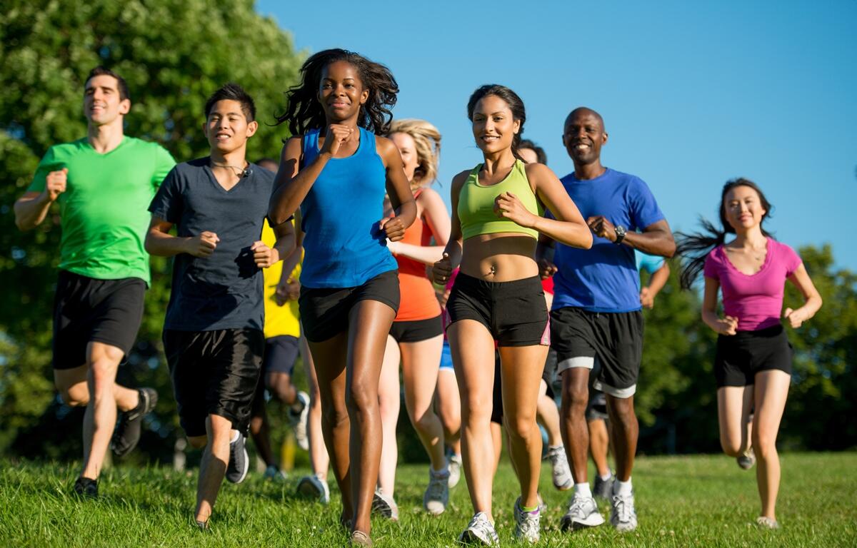 Group of people running together outdoors during a community fun run on a sunny day.
