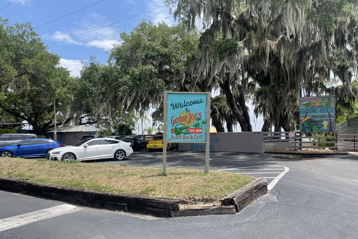 Gator Joe’s Beach Bar & Grill parking lot with cars parked under moss-covered oak trees near Lake Weir.