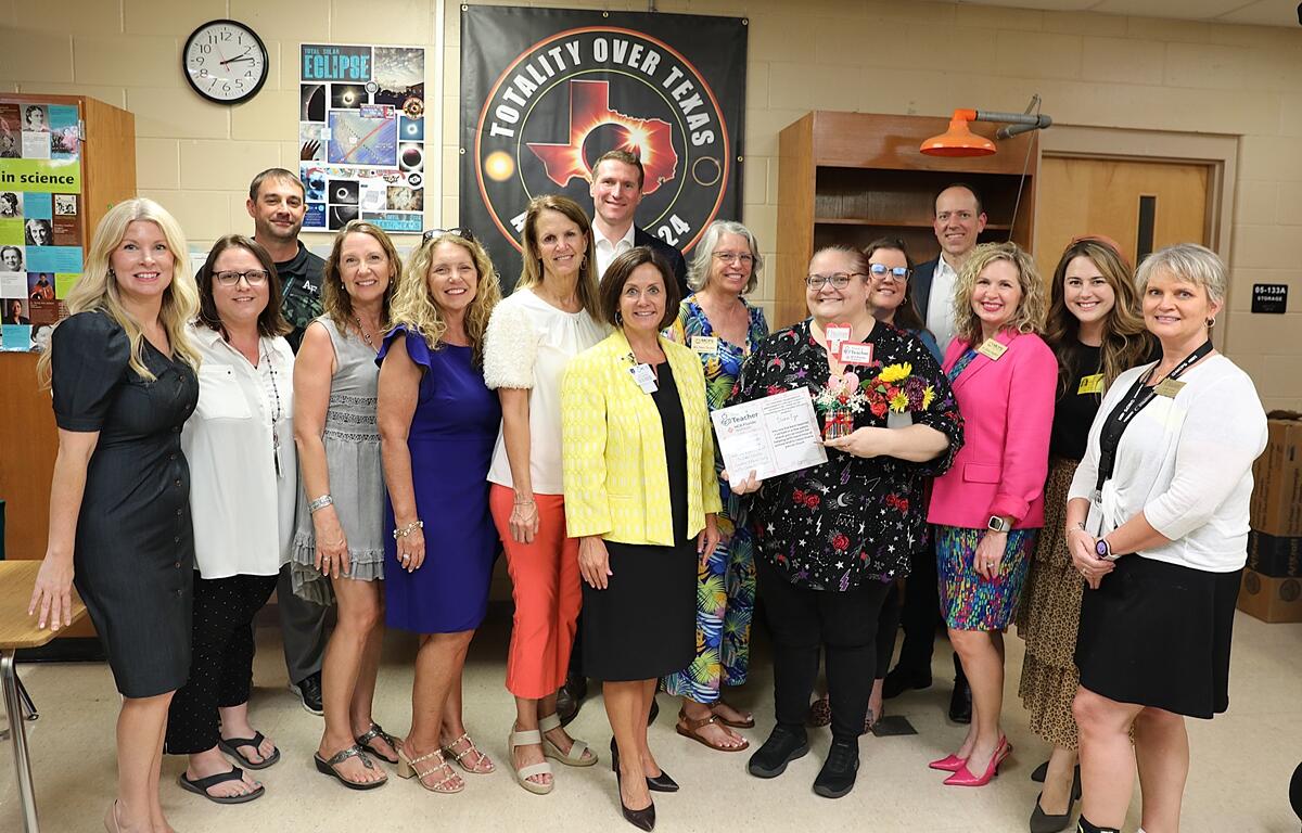 Group photo of Diana Fye holding her award and flowers, surrounded by school and community leaders including Meghan Magamoll, Lori Conrad, Isaiah Zirkle, Danielle Brewer, Alan Keesee, and others.