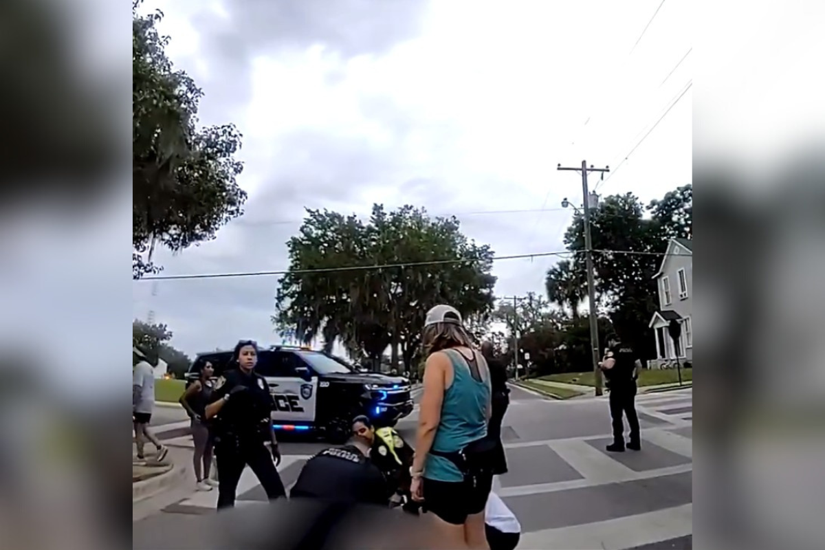Body cam footage captures a lady in a blue shirt and fellow officers with black uniforms helping out a collapsed man.