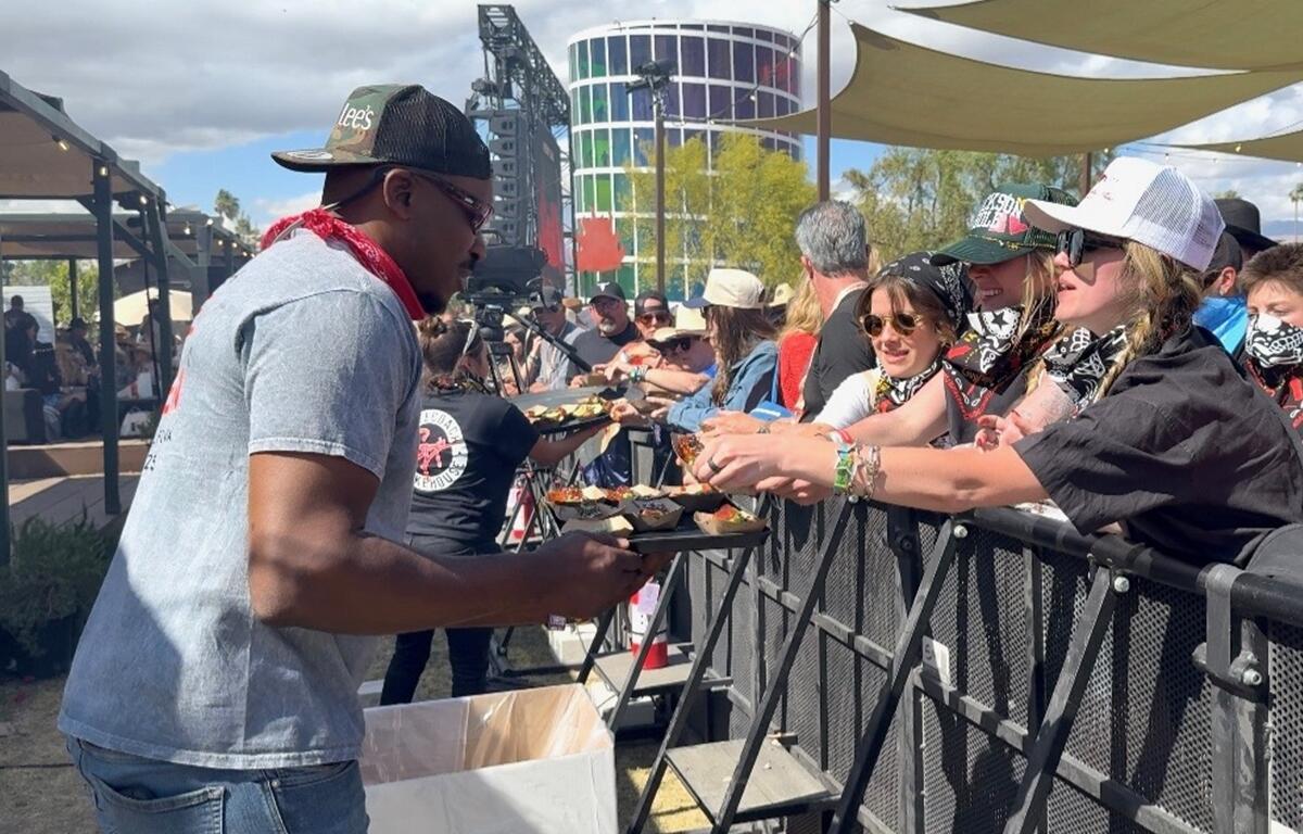 Rashad Jones, owner of Big Lee’s BBQ in Ocala, serves smoked barbecue samples to fans at Guy Fieri’s Smokehouse during the Stagecoach Music Festival in Indio, California.