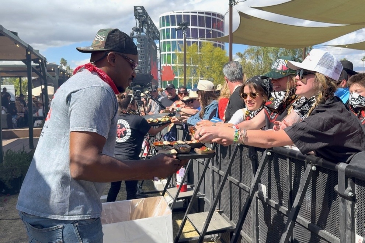 Rashad Jones, owner of Big Lee’s BBQ in Ocala, serves smoked barbecue samples to fans at Guy Fieri’s Smokehouse during the Stagecoach Music Festival in Indio, California.