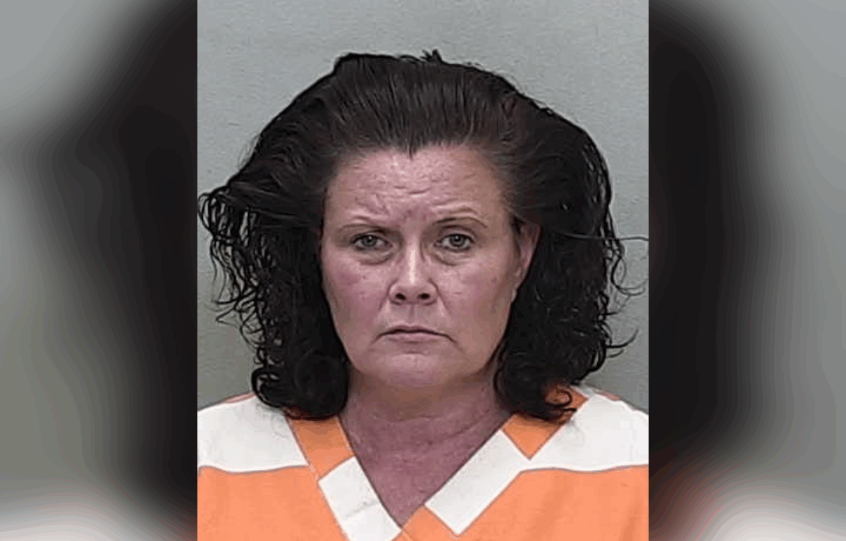 Mugshot of Amy Linn Ramirez, a woman with shoulder-length dark curly hair, wearing an orange and white jail uniform, against a plain gray background.