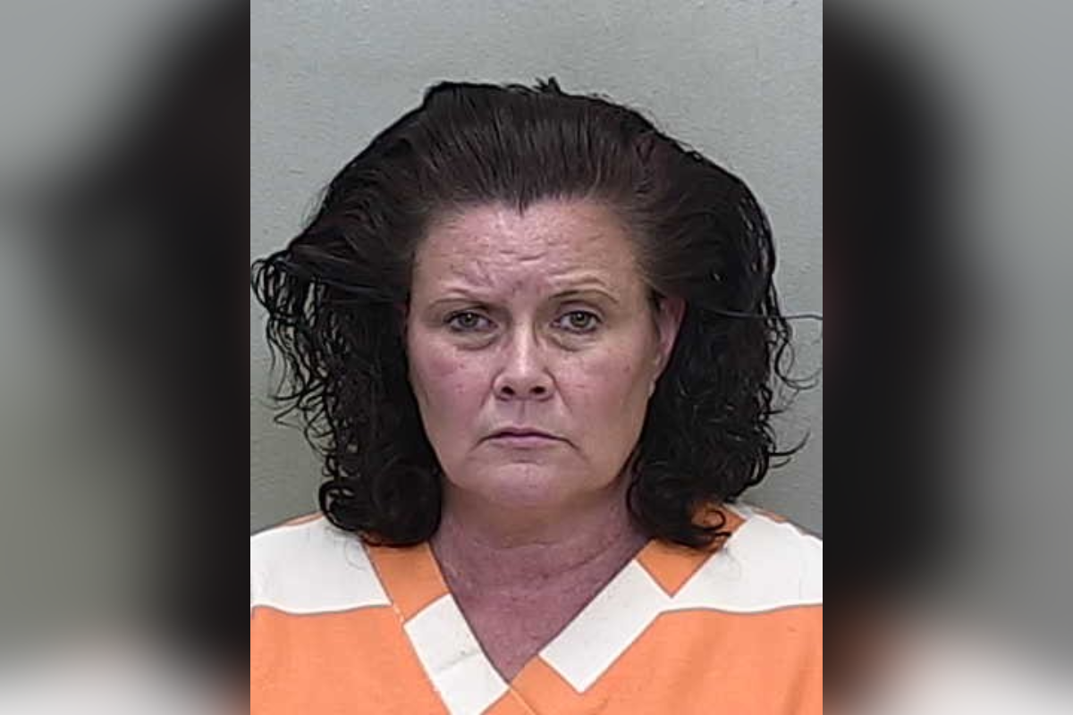 Mugshot of Amy Linn Ramirez, a woman with shoulder-length dark curly hair, wearing an orange and white jail uniform, against a plain gray background.