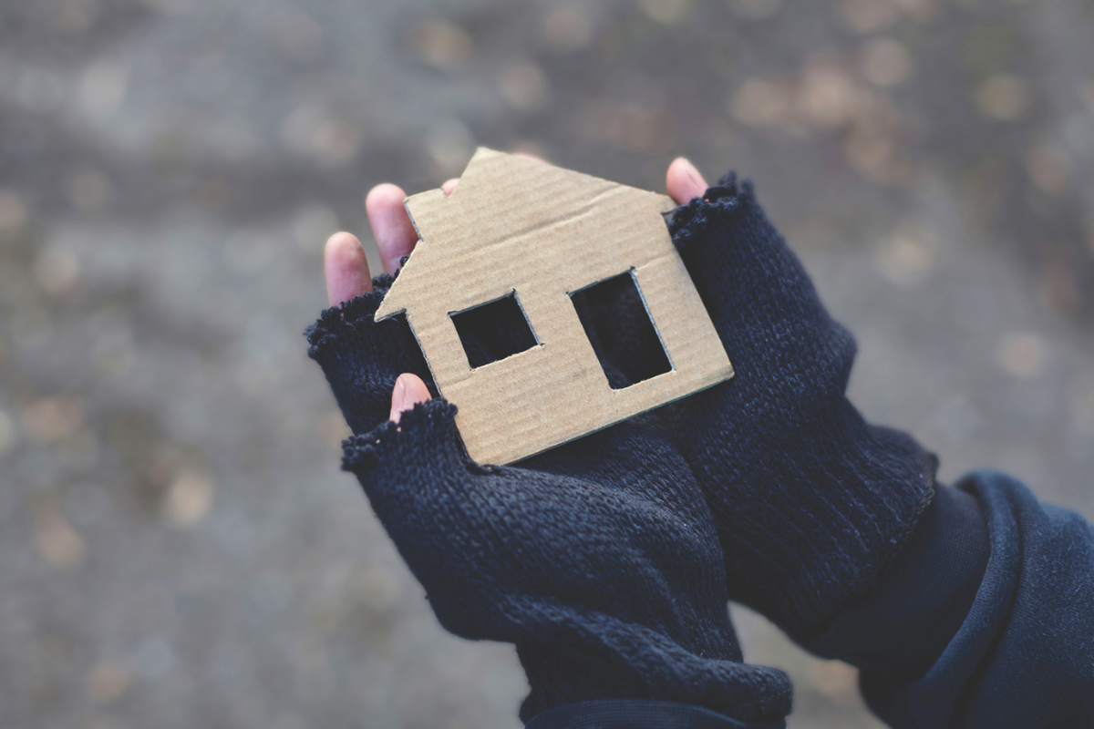 Girl holds a cardboard house, longing for one of her own.