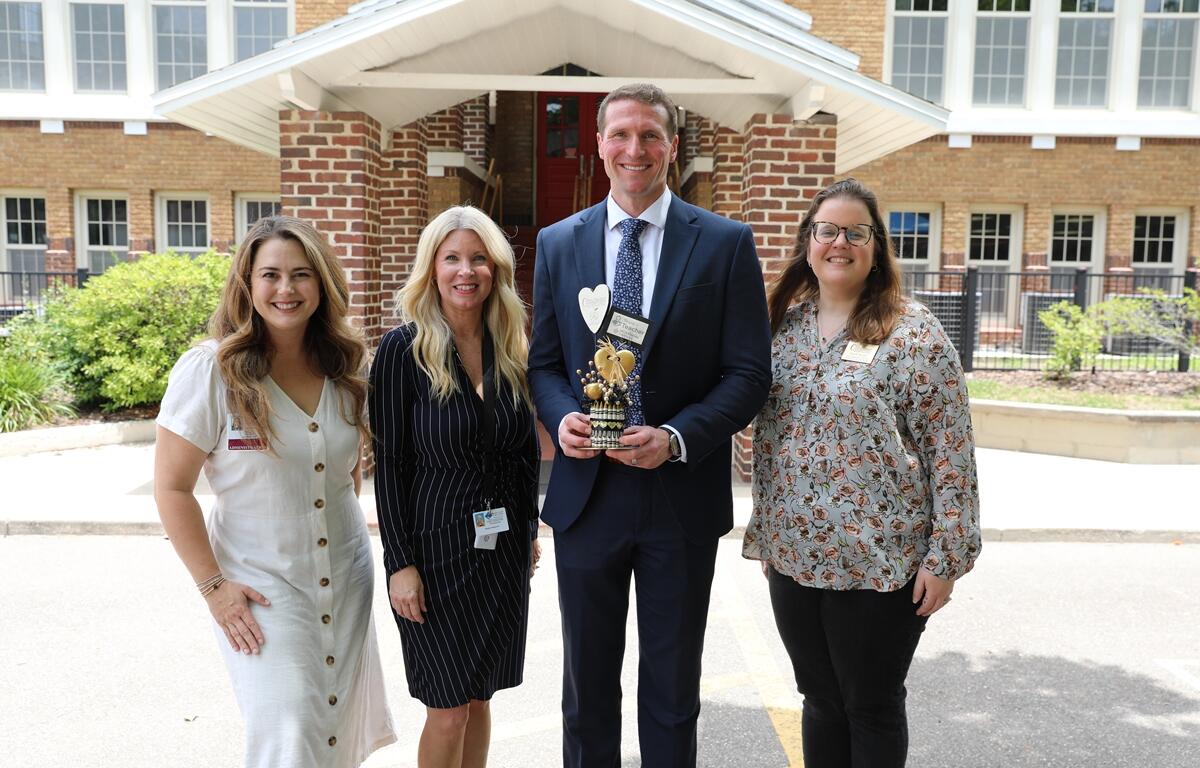 Isaiah Zirkle holds a gold award while standing with three women in front of Eighth Street Elementary during the “Thank a Teacher” recognition event.