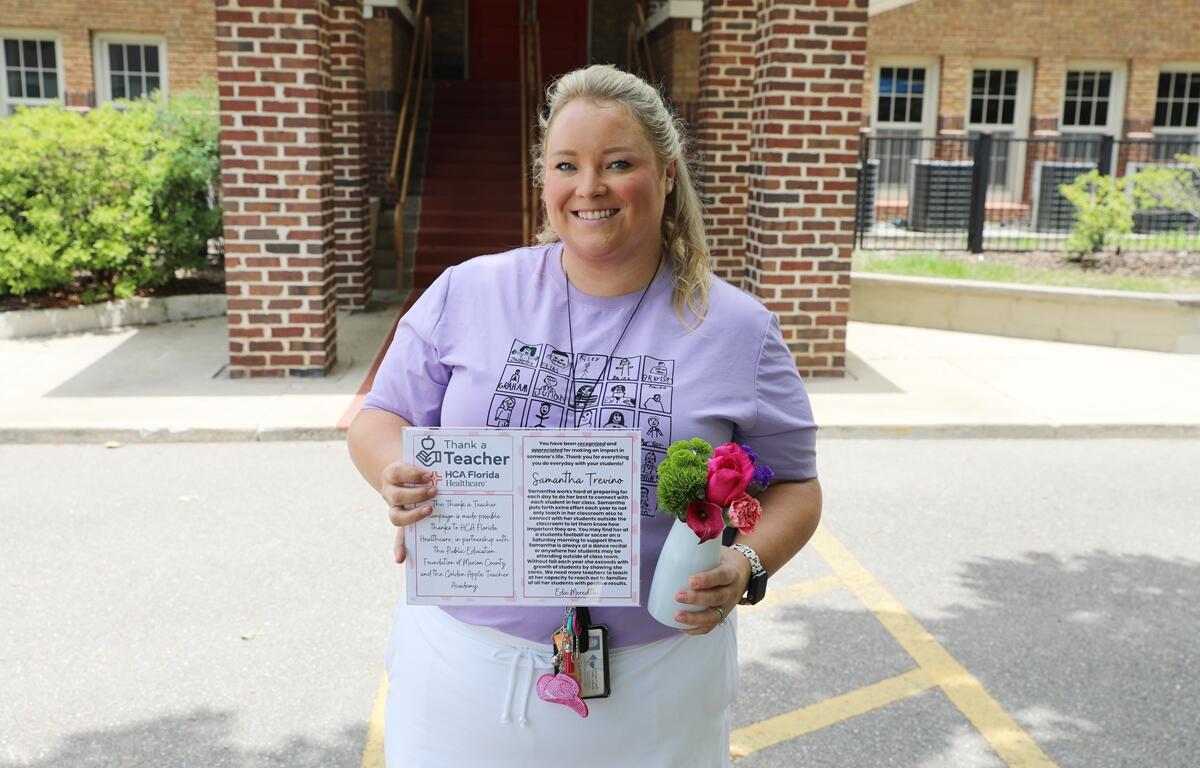 Samantha Trevino smiles while holding a flower arrangement and her “Thank a Teacher” award outside Eighth Street Elementary School.