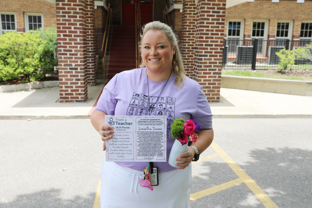 Samantha Trevino smiles while holding a flower arrangement and her “Thank a Teacher” award outside Eighth Street Elementary School.