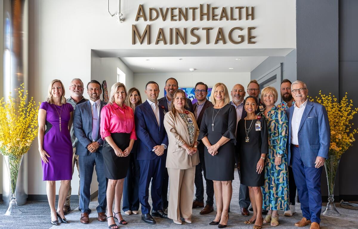 Group of community leaders standing beneath the "AdventHealth Mainstage" sign at the Reilly Arts Center during a dedication event.