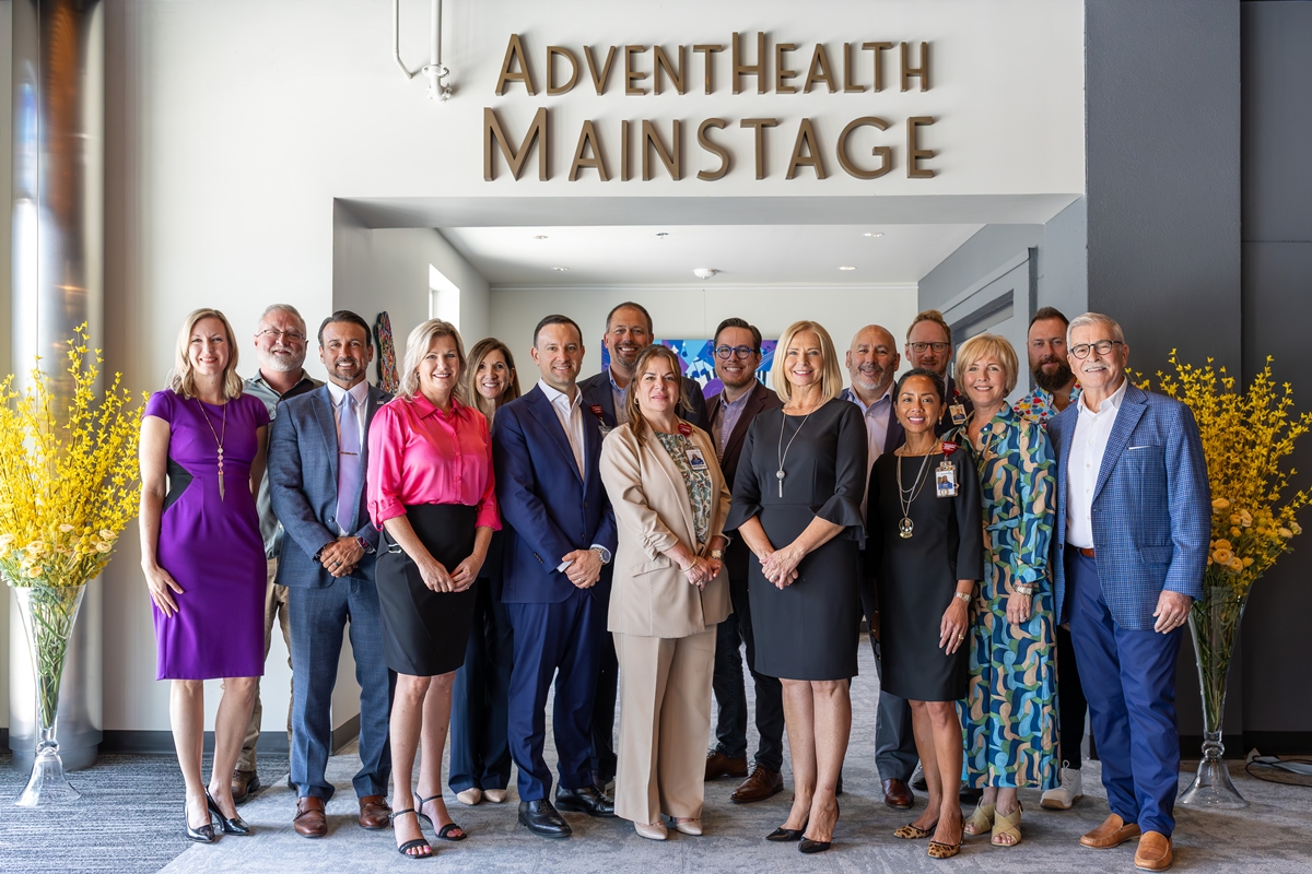 Group of community leaders standing beneath the "AdventHealth Mainstage" sign at the Reilly Arts Center during a dedication event.