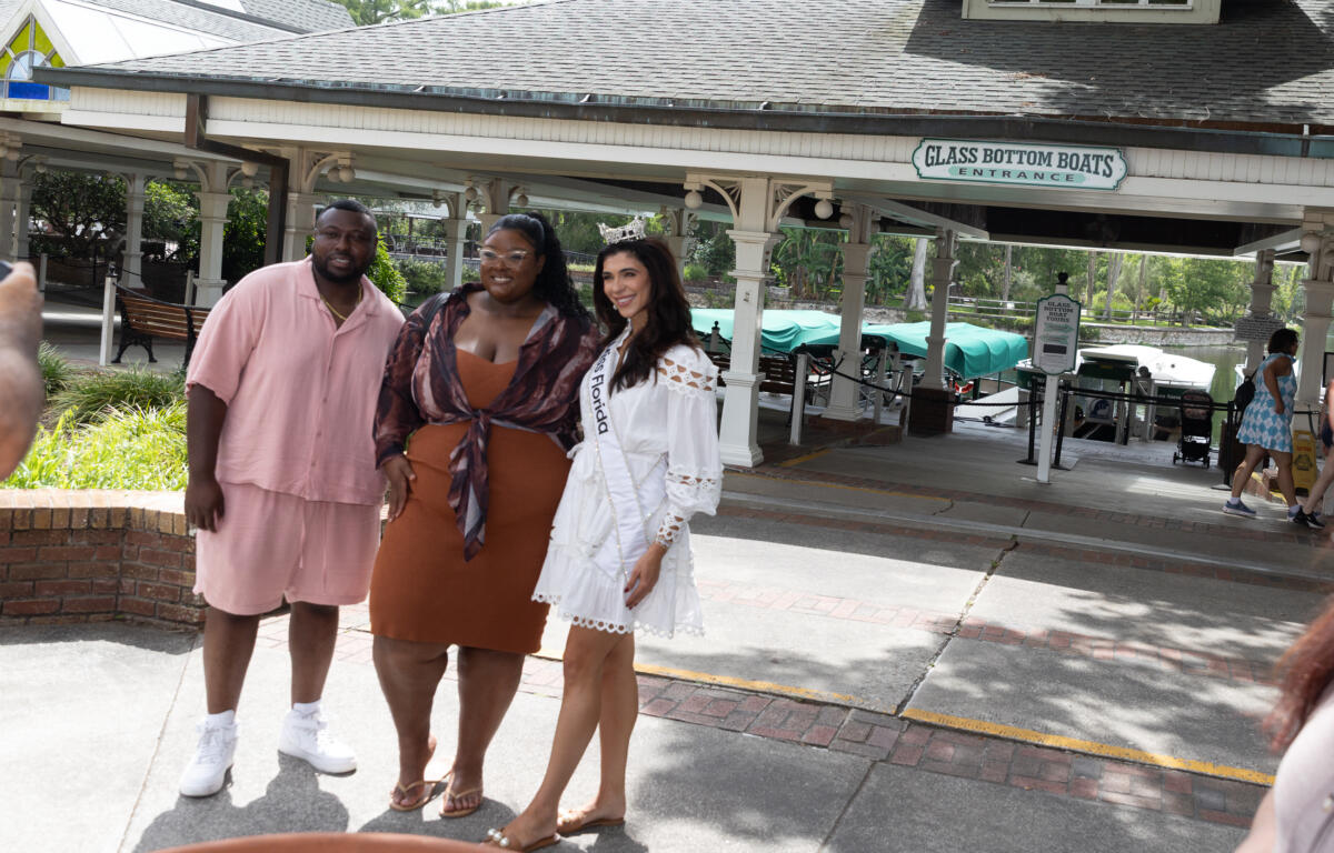 Miss Florida posing with two guests in front of the glass-bottom boat boarding area at Silver Springs.