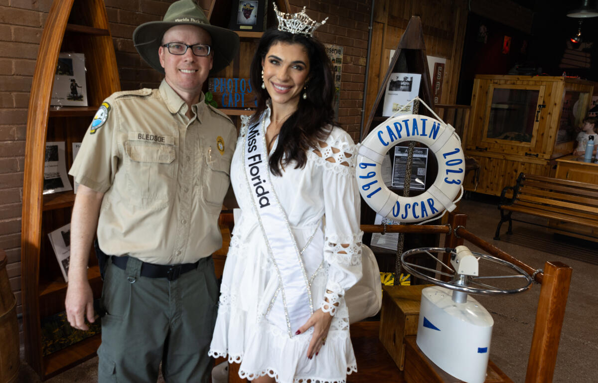 Miss Florida smiling while walking up the dock ramp in a captain’s hat near Silver Springs tour boats.