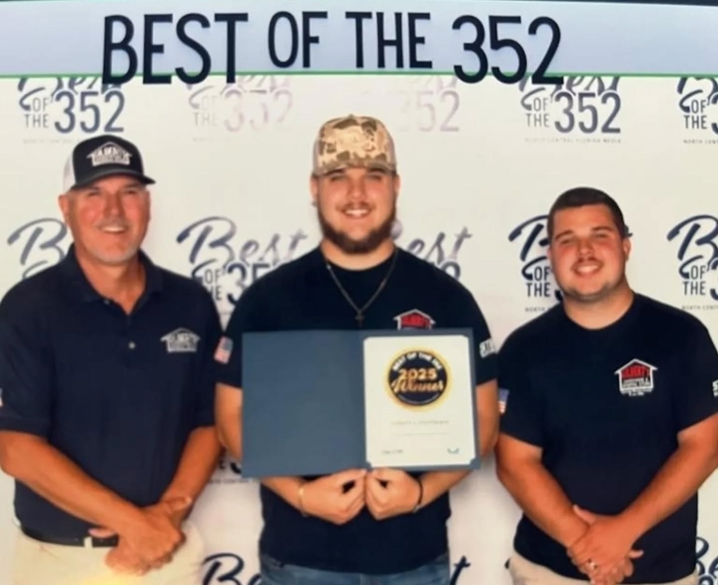 Three men from the Gilbert family pose with a 2025 Best of the 352 award certificate in front of a branded event backdrop.