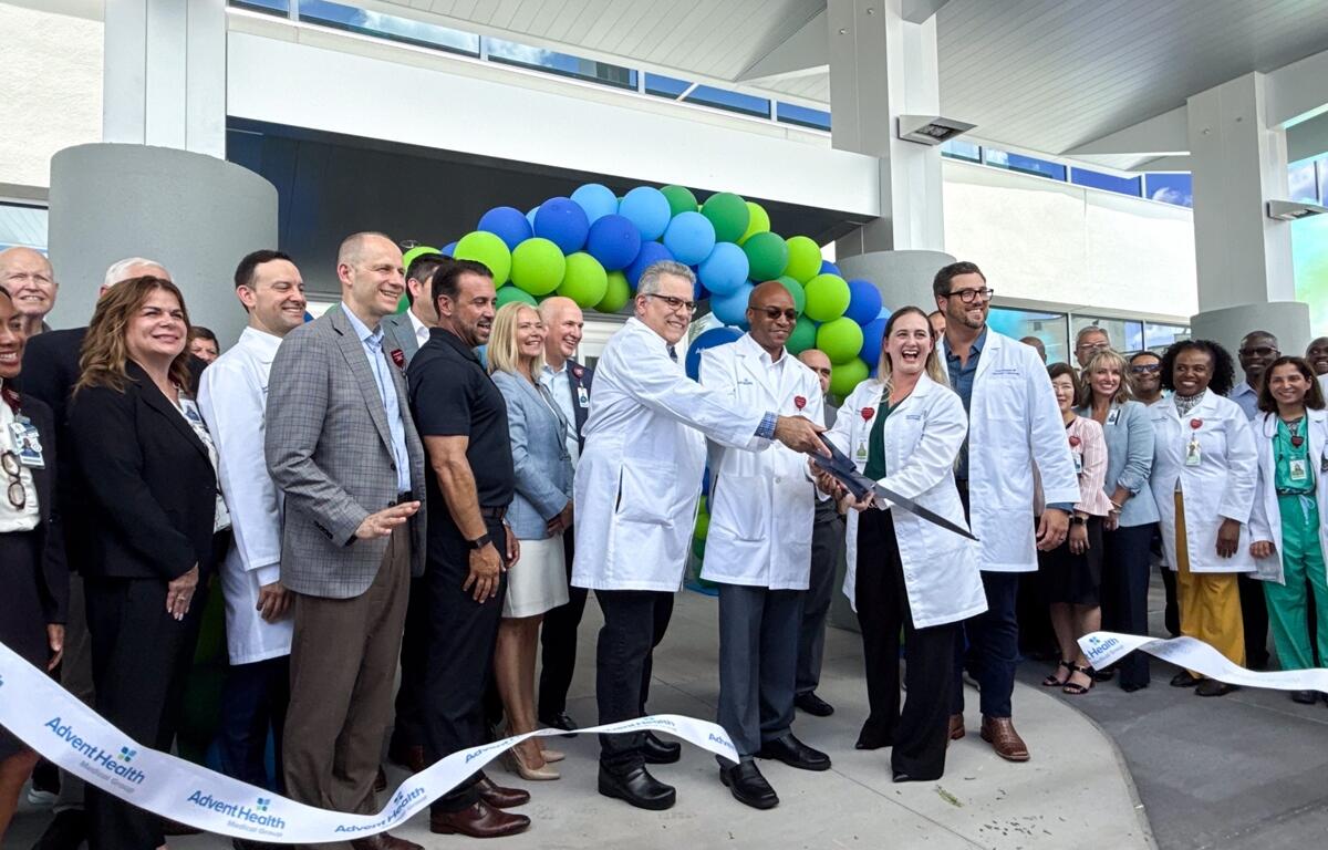 Doctors and staff hold large scissors and cut the ribbon surrounded by colleagues at AdventHealth Ocala’s new Medical Office Building grand opening.