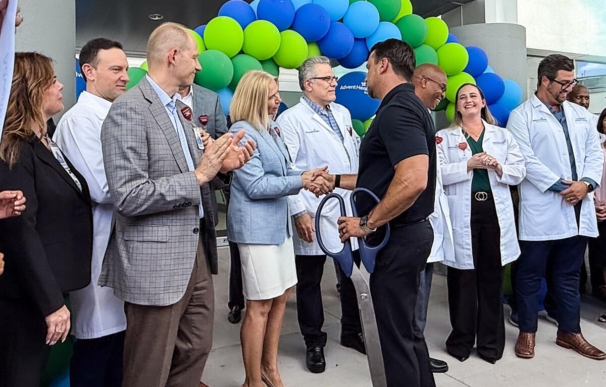 Mayor Ben Marciano shakes hands with a medical professional as AdventHealth Ocala staff and doctors applaud at the ribbon cutting event.