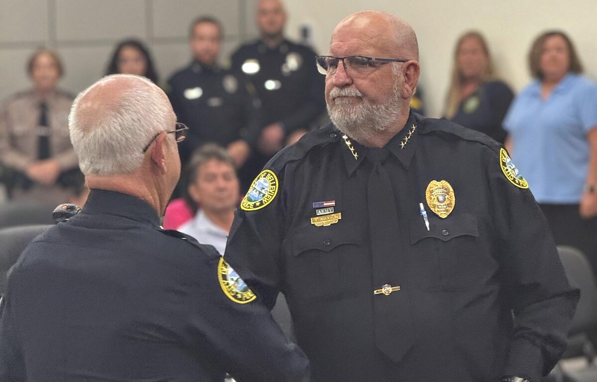 Belleview Police Chief Terry Holland shakes hands with Assistant Chief Larry Bryan during a promotion ceremony at the Belleview City Commission meeting.