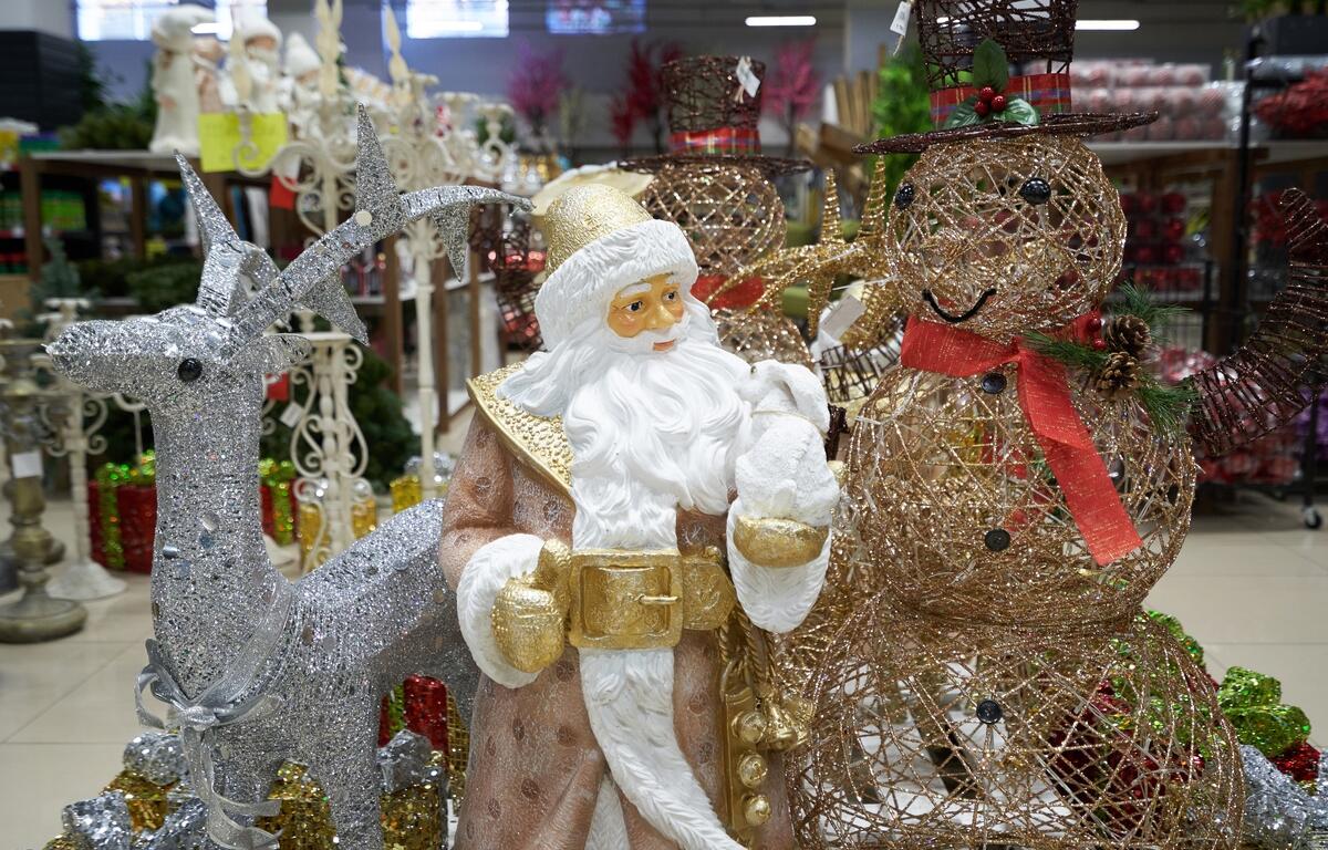 Santa figurine, glittering reindeer, and wire snowmen on display in a festive indoor holiday market setting.