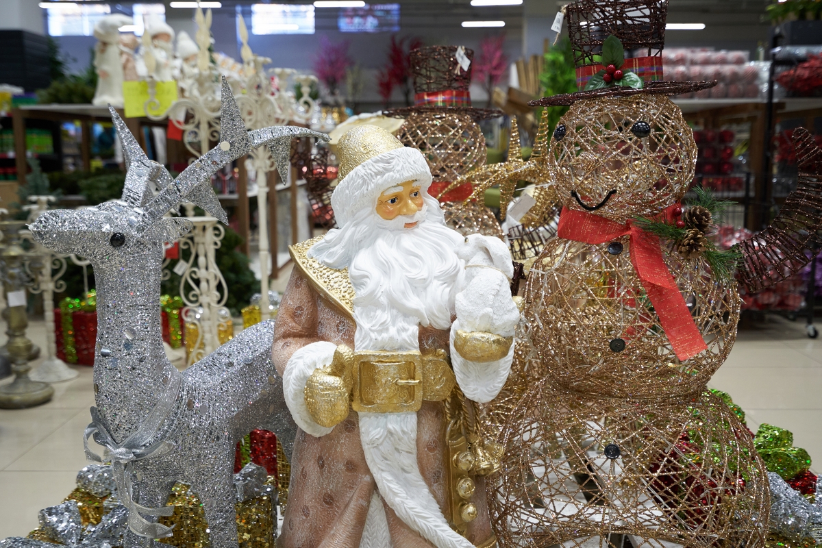 Santa figurine, glittering reindeer, and wire snowmen on display in a festive indoor holiday market setting.