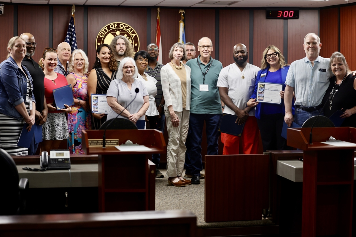 Citizens Academy graduates hold certificates while standing for a group photo in the council chambers.