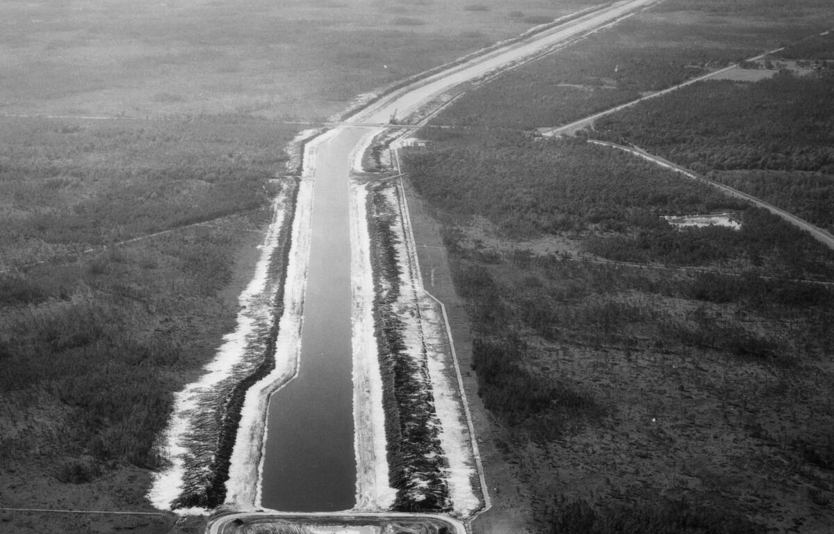 Aerial view of a partially constructed section of the Cross Florida Barge Canal cutting through forested land in central Florida.