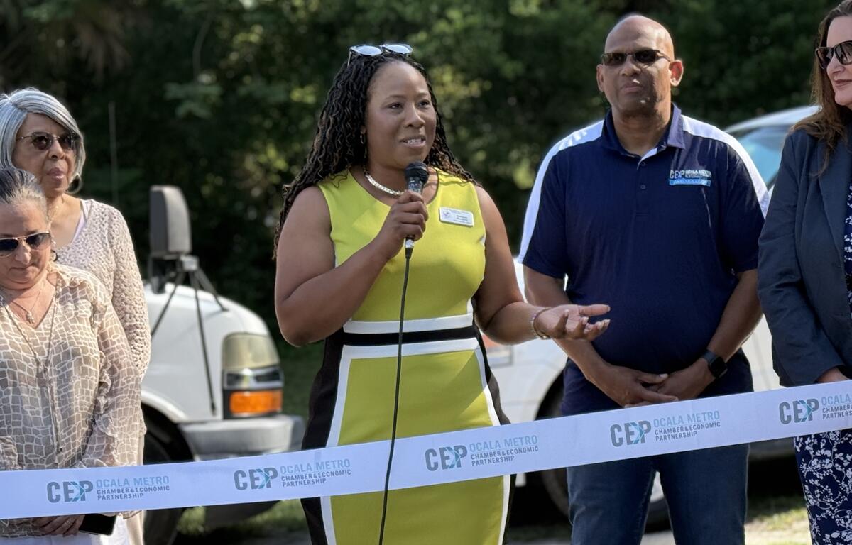 LaVonda Goodsen speaks at a microphone during ribbon cutting event in Ocala.