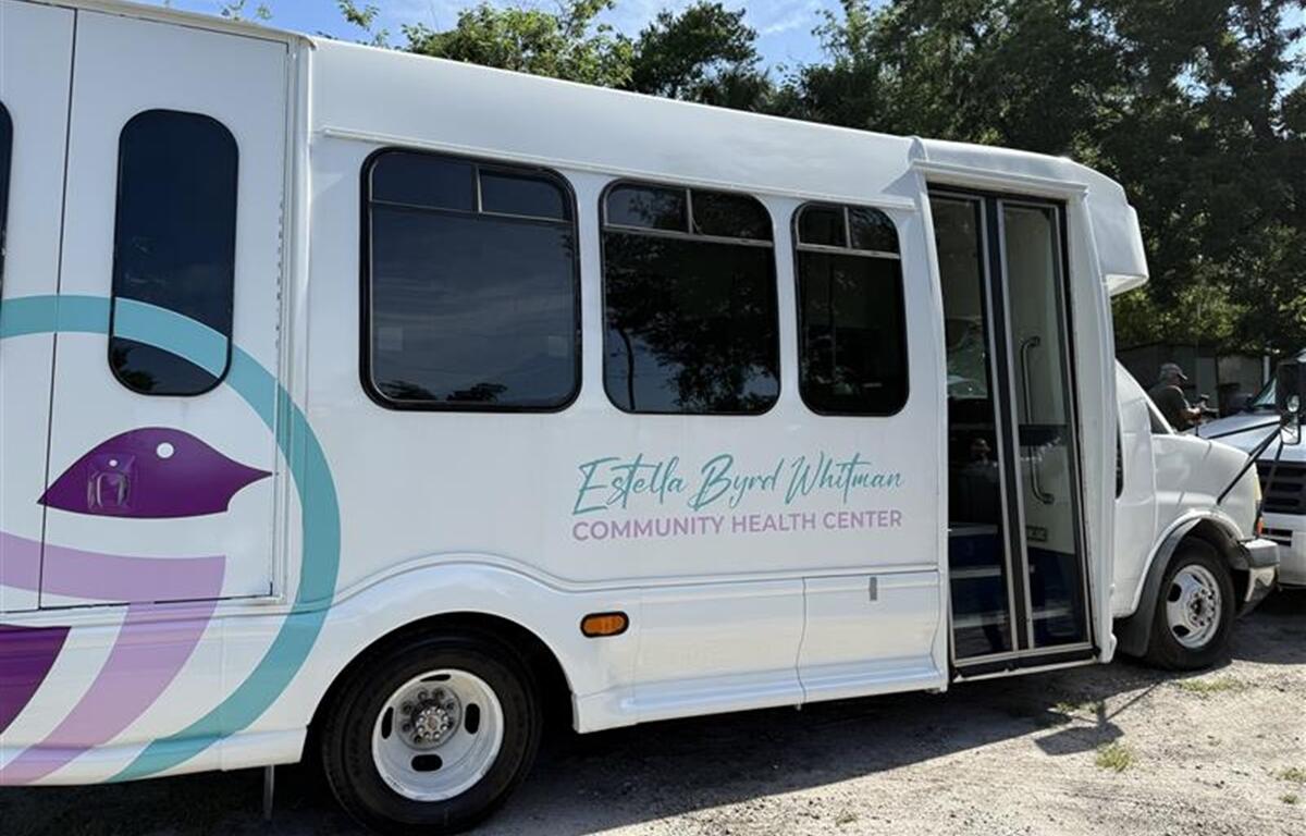 White passenger vehicle with Estella Byrd Whitman Community Health Center logo parked outdoors.