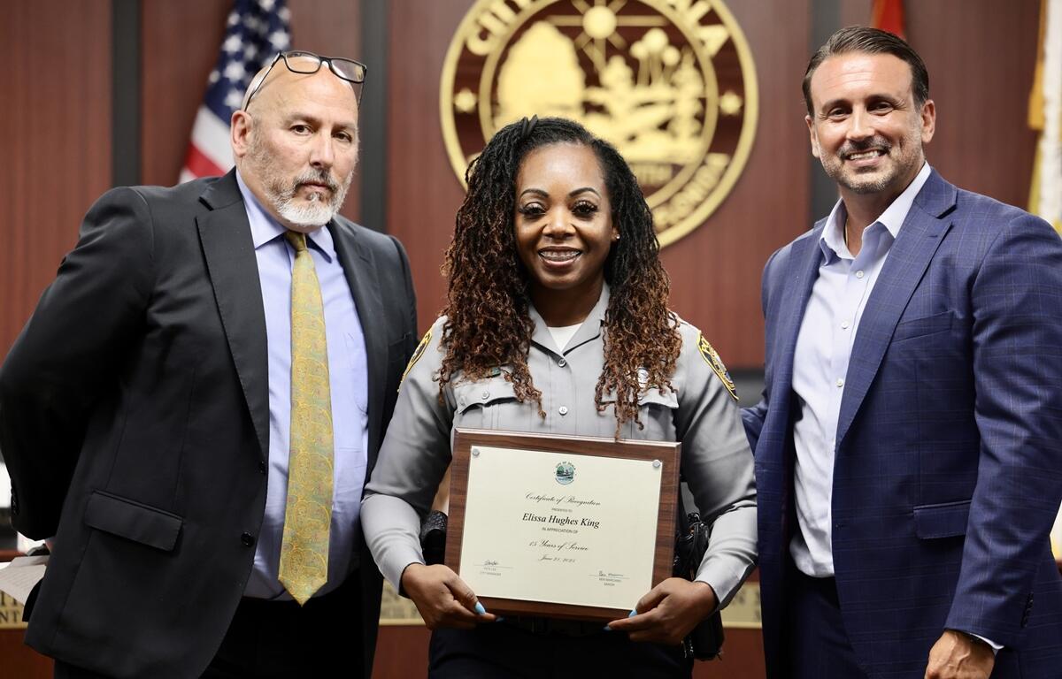 Elissa Hughes-King smiles while accepting a framed certificate during the city council meeting.