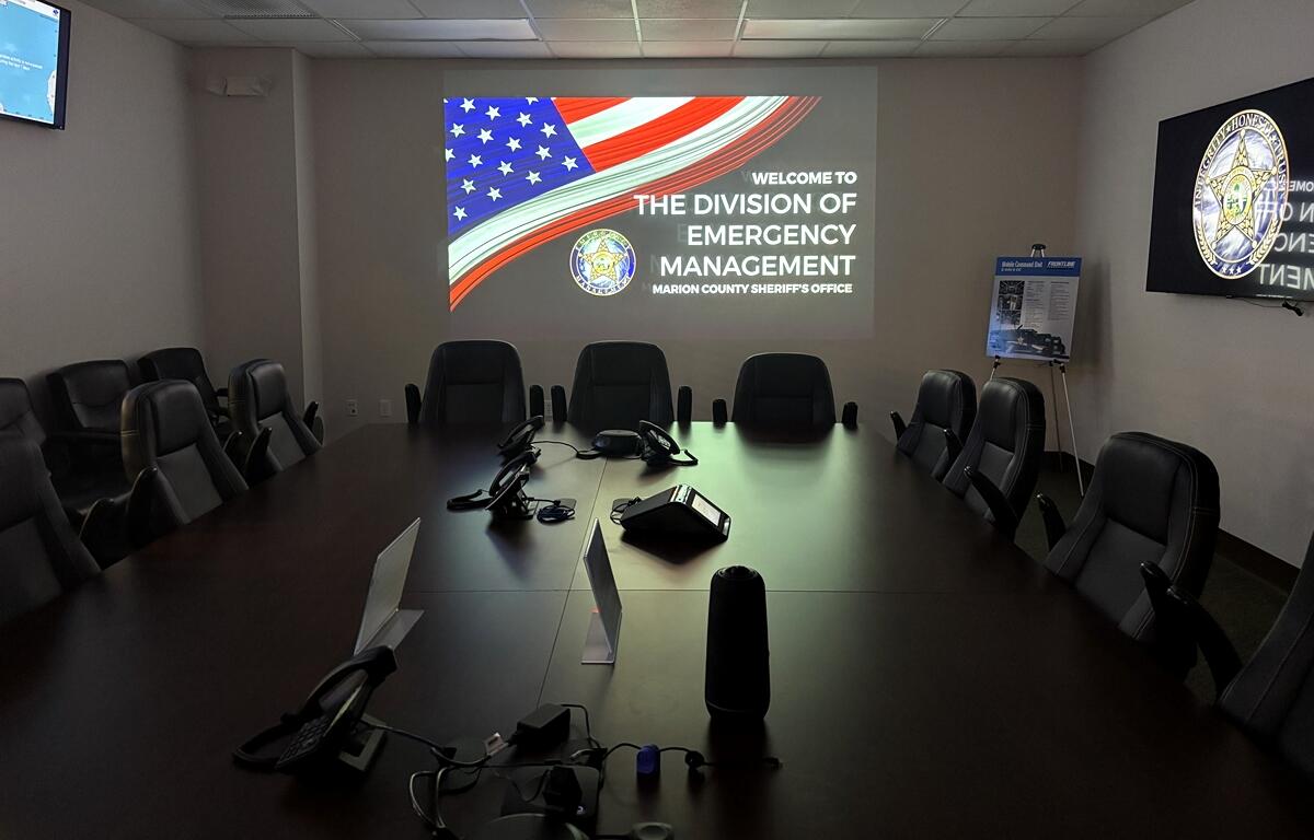 Conference-style planning room at Marion County Emergency Operations Center with a projection screen and multiple chairs.