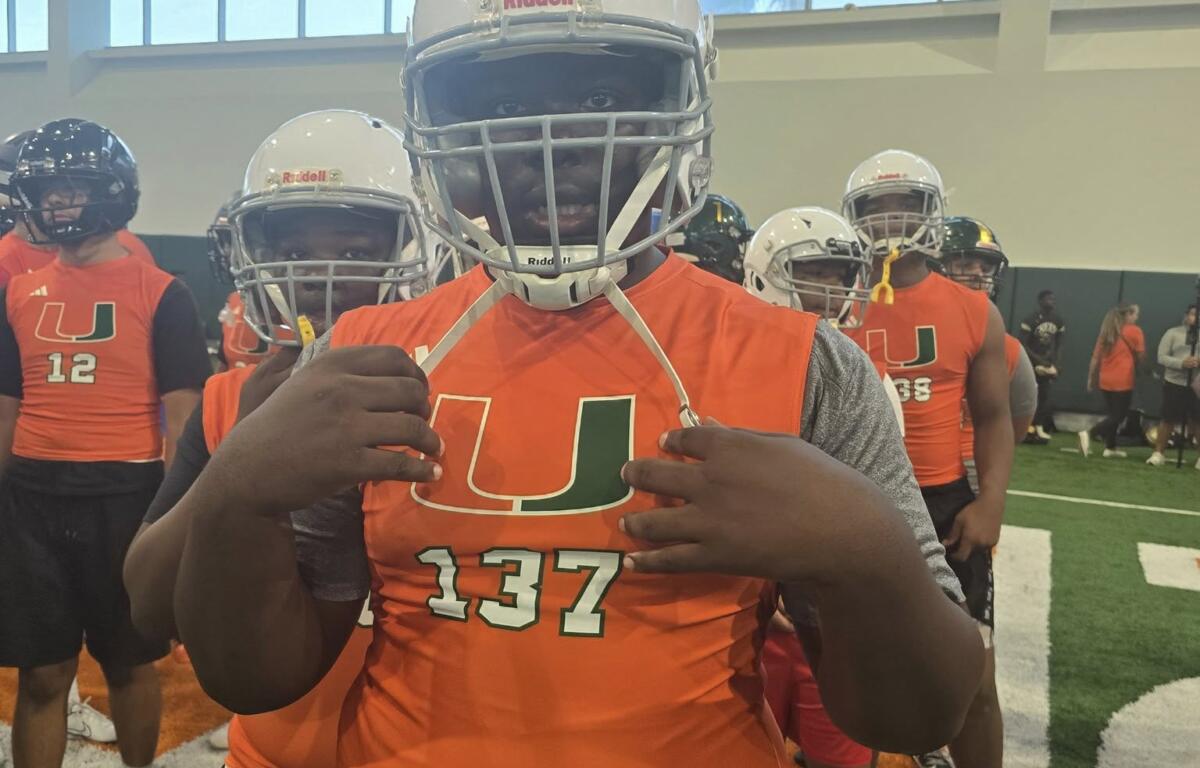 A youth football player wearing jersey #137 points at the “U” on his chest while posing for the camera during the Empowered Linemen Academy event.