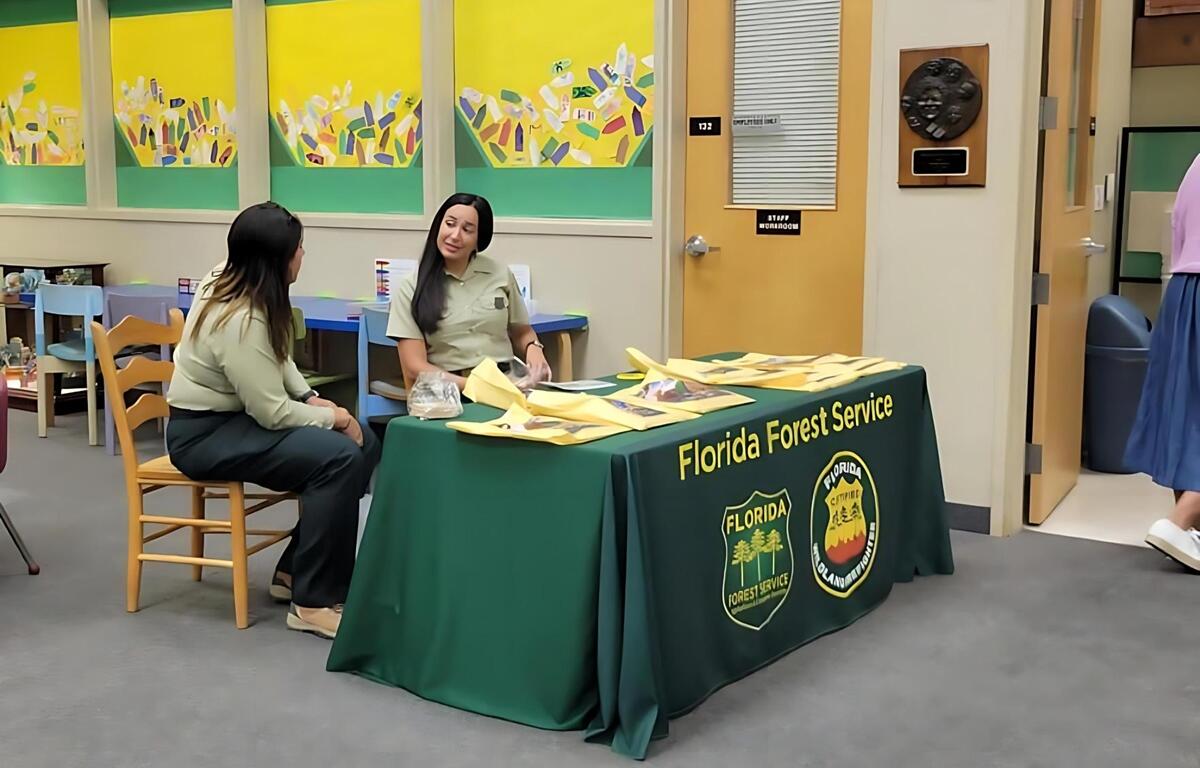  Two women in uniform speak at a Florida Forest Service information table inside the Marion County Public Library.