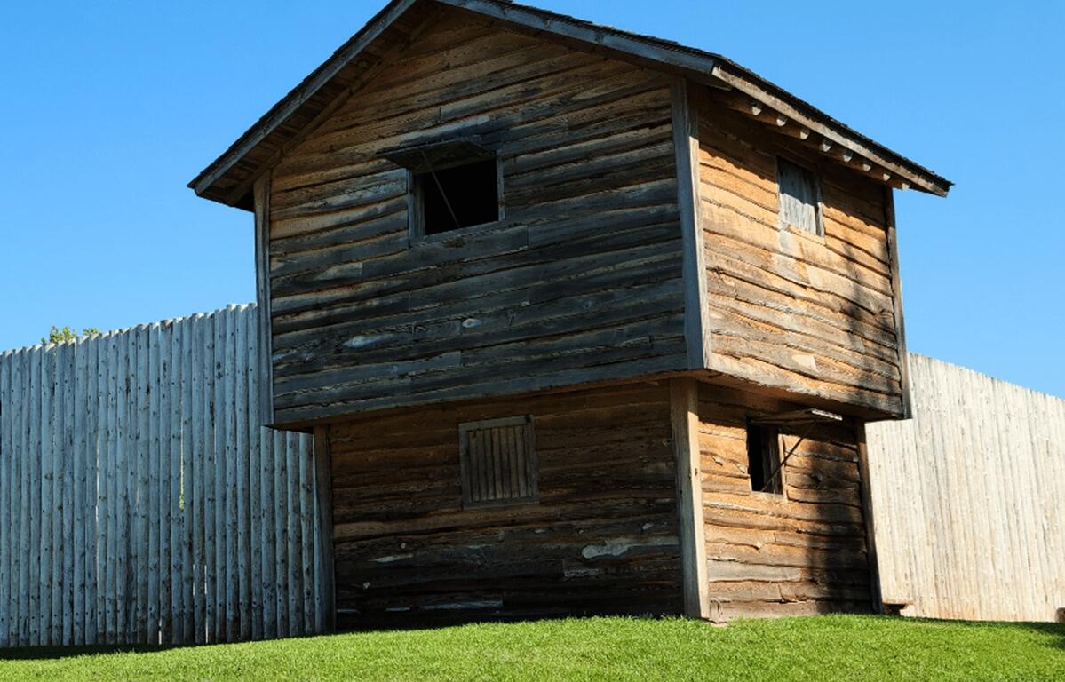Reconstructed wooden blockhouse at Fort King National Historic Landmark in Ocala, Florida, under a clear blue sky.