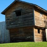 Reconstructed wooden blockhouse at Fort King National Historic Landmark in Ocala, Florida, under a clear blue sky.