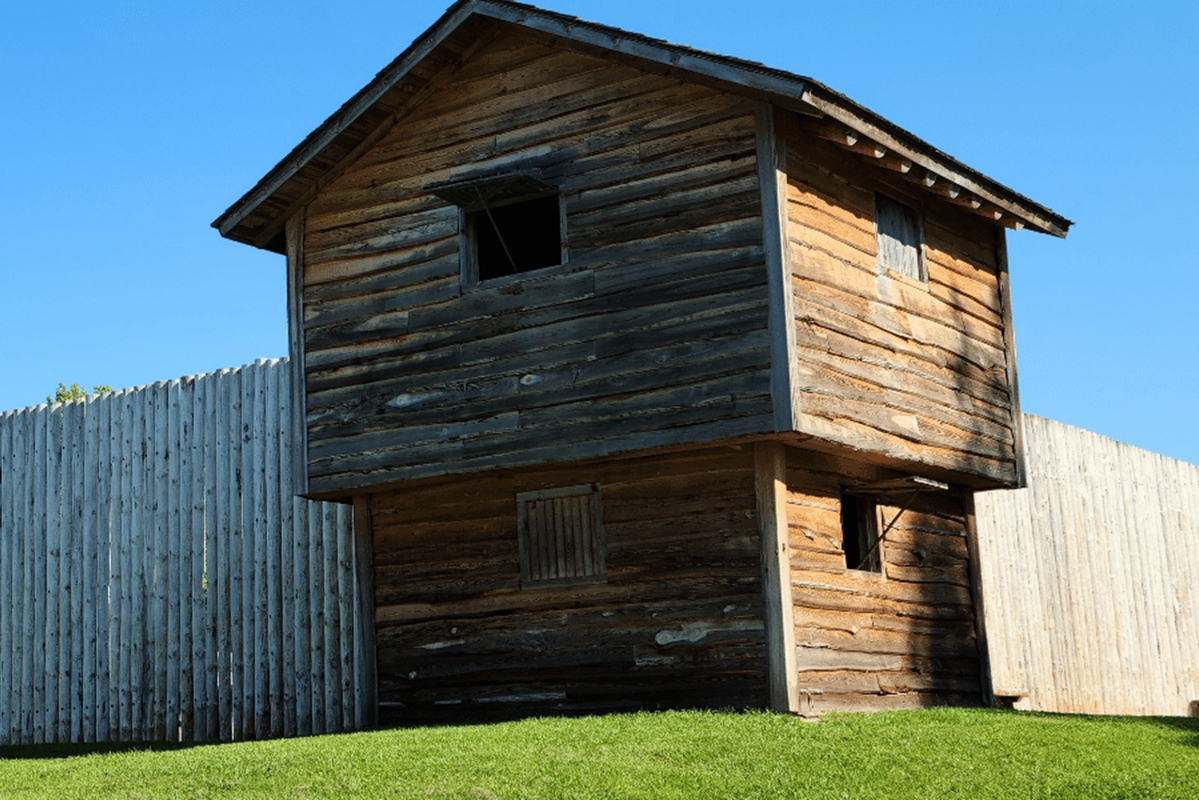 Reconstructed wooden blockhouse at Fort King National Historic Landmark in Ocala, Florida, under a clear blue sky.