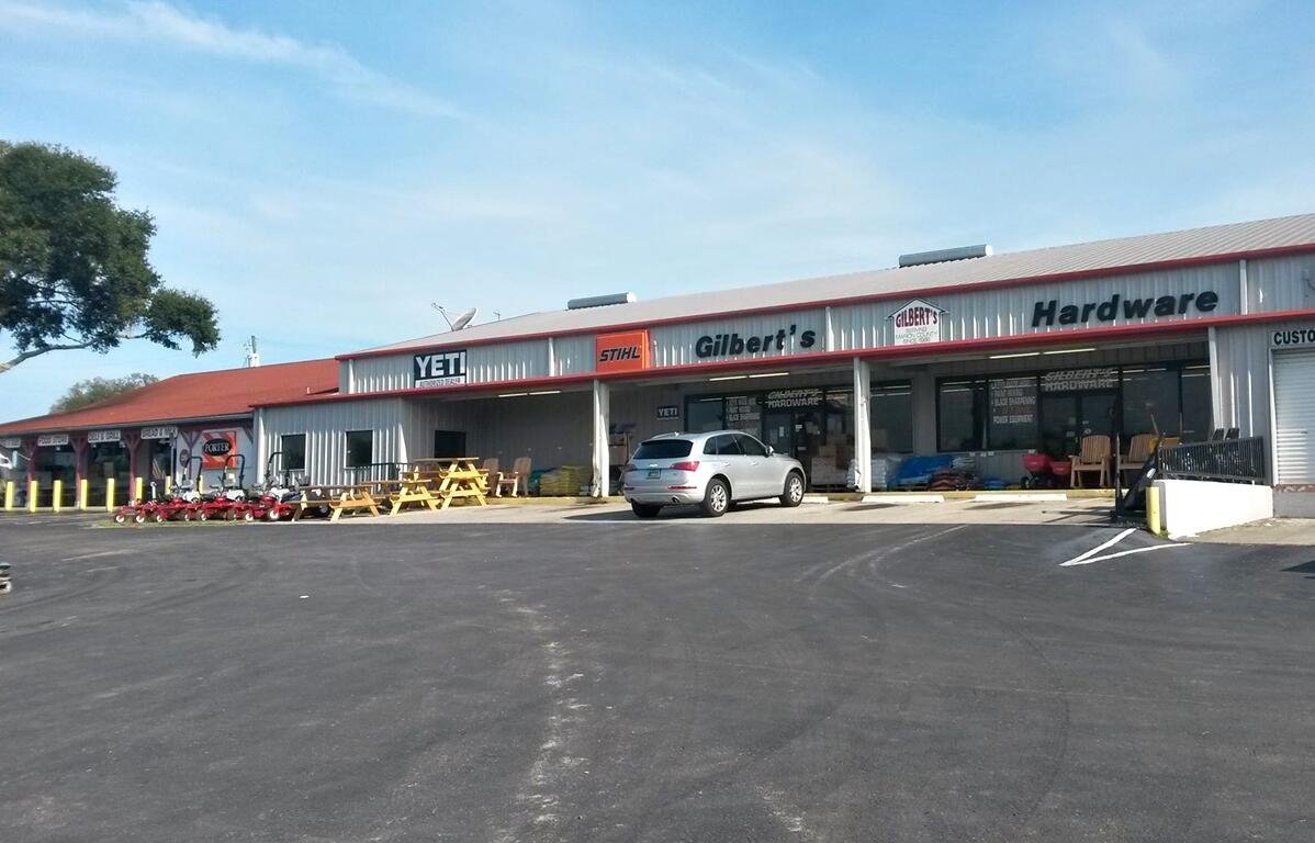 Exterior view of Gilbert’s Hardware & General Store with STIHL and YETI signage, a parked vehicle, and lawn equipment displayed outside.