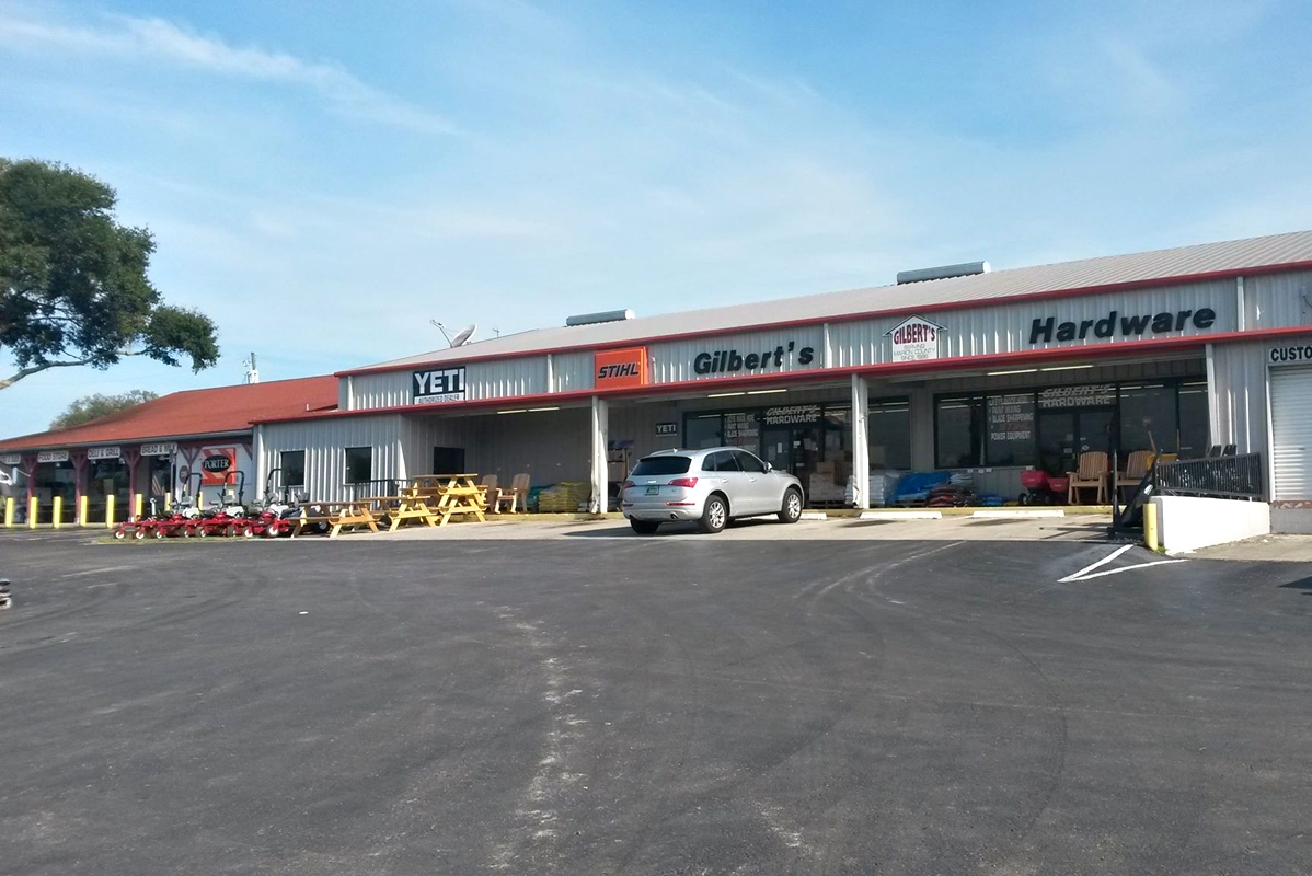 Exterior view of Gilbert’s Hardware & General Store with STIHL and YETI signage, a parked vehicle, and lawn equipment displayed outside.