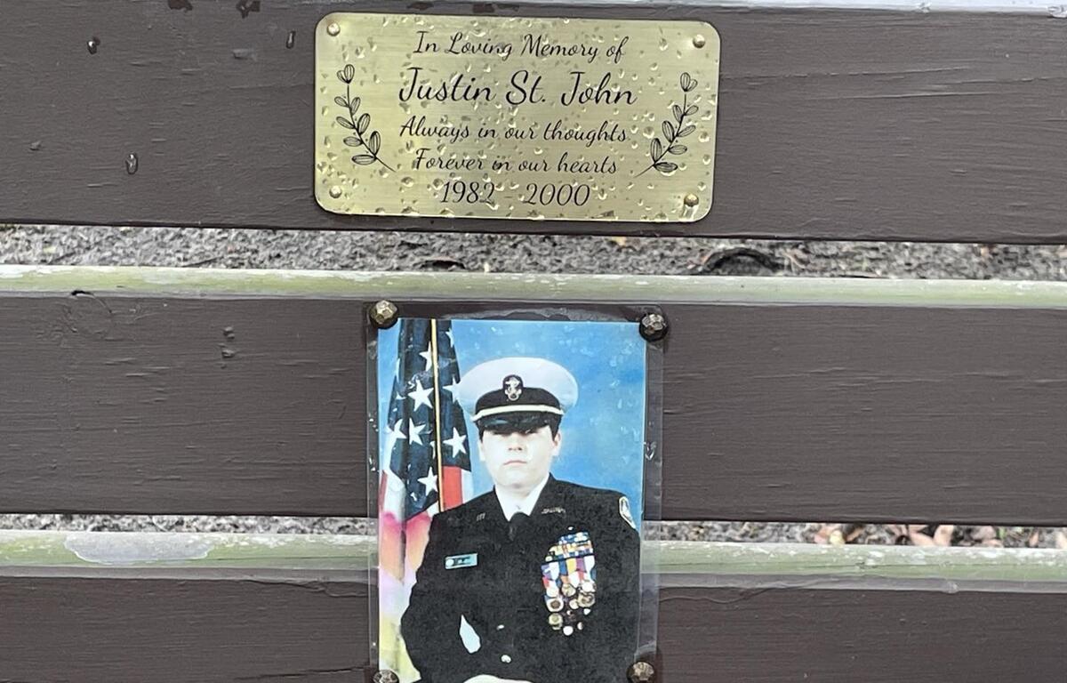 Photo of Justin St. John in military uniform and engraved memorial plaque on a wooden bench at Squirrel Ridge Park in Gainesville.