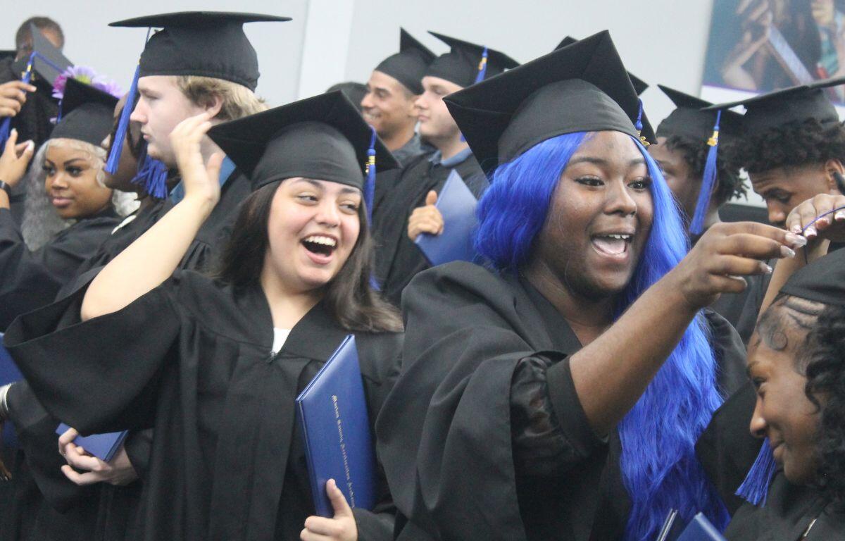 Students in graduation caps and gowns smile and cheer while flipping tassels during the Acceleration Academy graduation ceremony.