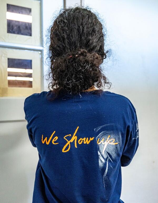 Back of a volunteer’s shirt reading “We show up” during renovation work at Heart of the Park in Ocala.
