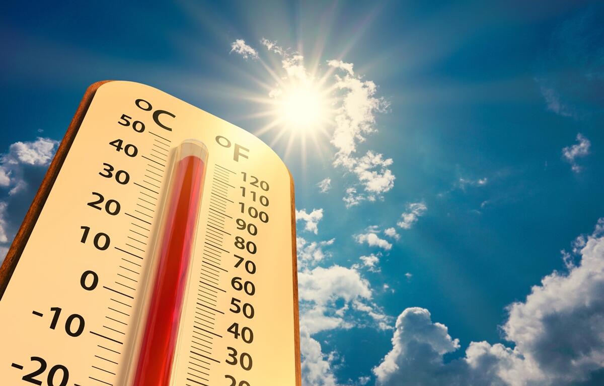 Thermometer showing temperatures above 100 degrees under bright sun and blue sky with scattered clouds.
