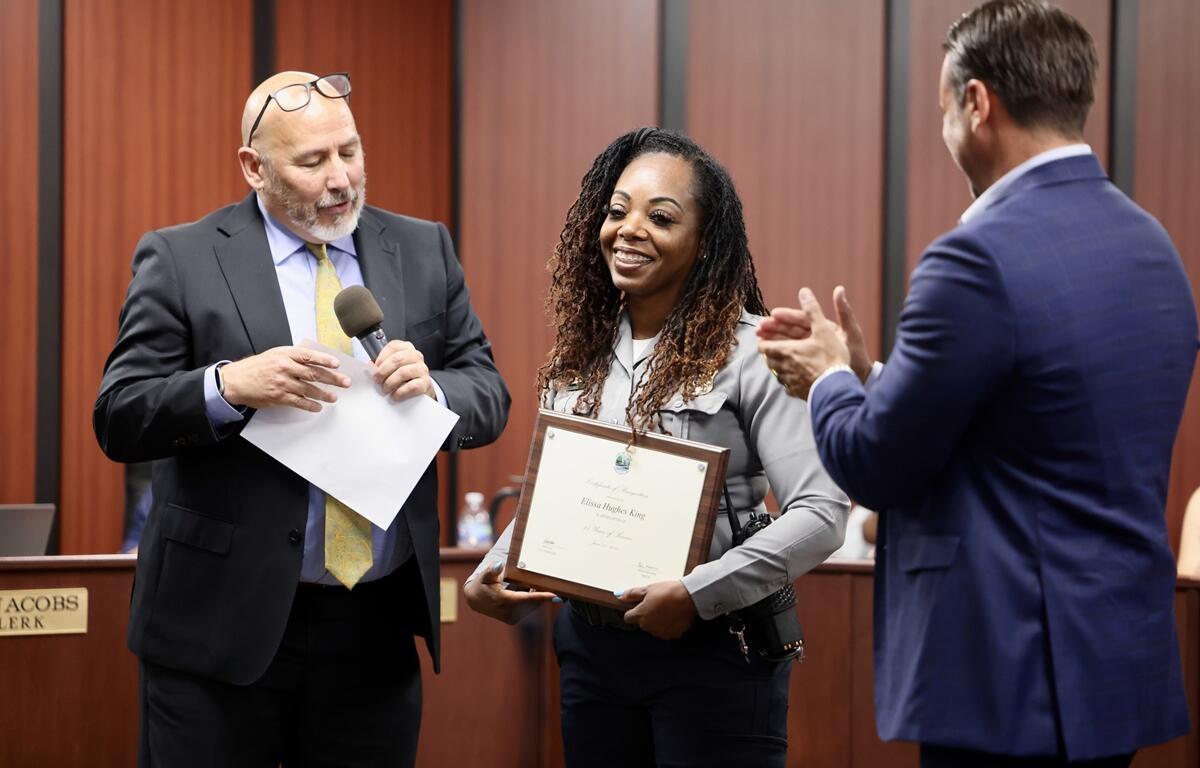 Elissa Hughes-King smiles while accepting a framed certificate during the city council meeting.