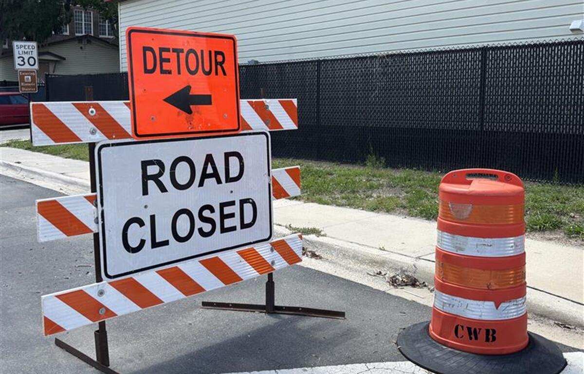 Detour and road closed signs in front of construction fencing near a school zone in Ocala.