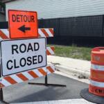 Detour and road closed signs in front of construction fencing near a school zone in Ocala.
