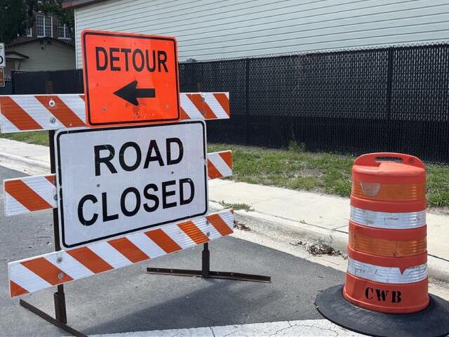Detour and road closed signs in front of construction fencing near a school zone in Ocala.