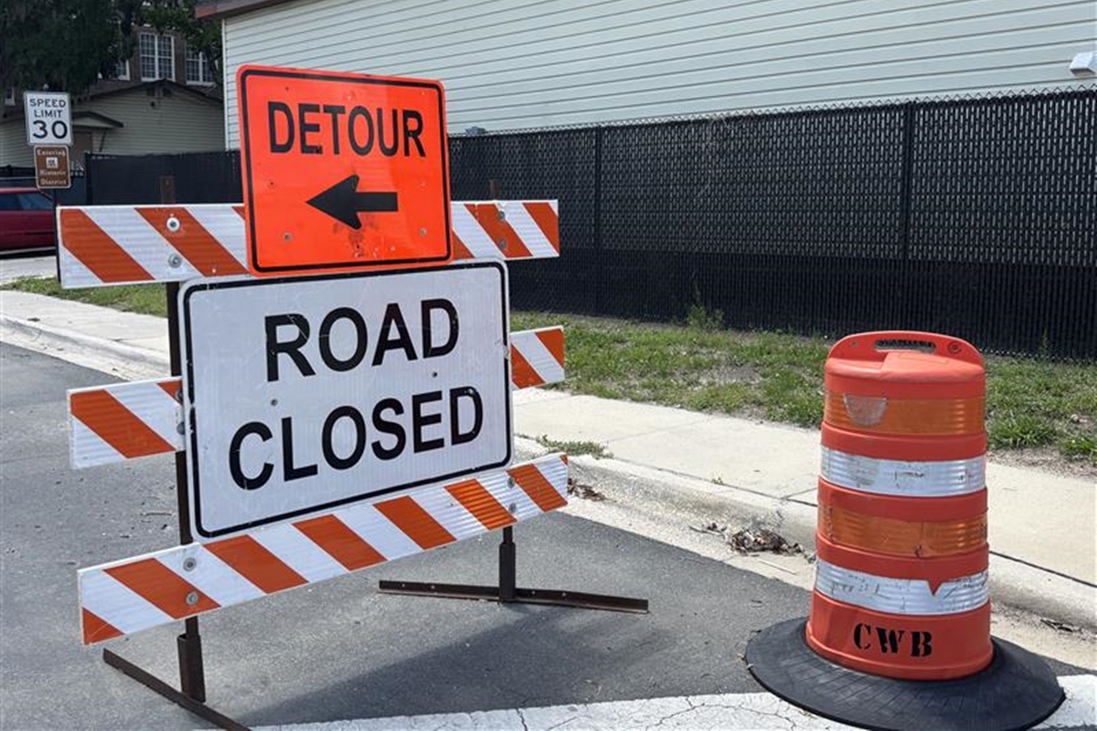 Detour and road closed signs in front of construction fencing near a school zone in Ocala.