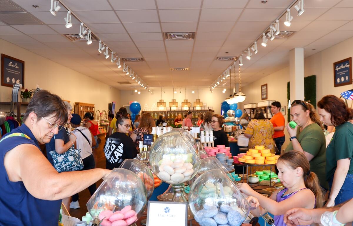 Customers browse colorful soaps and bath items displayed in glass jars inside Magnolia Soap and Bath Company during its grand opening in Ocala.