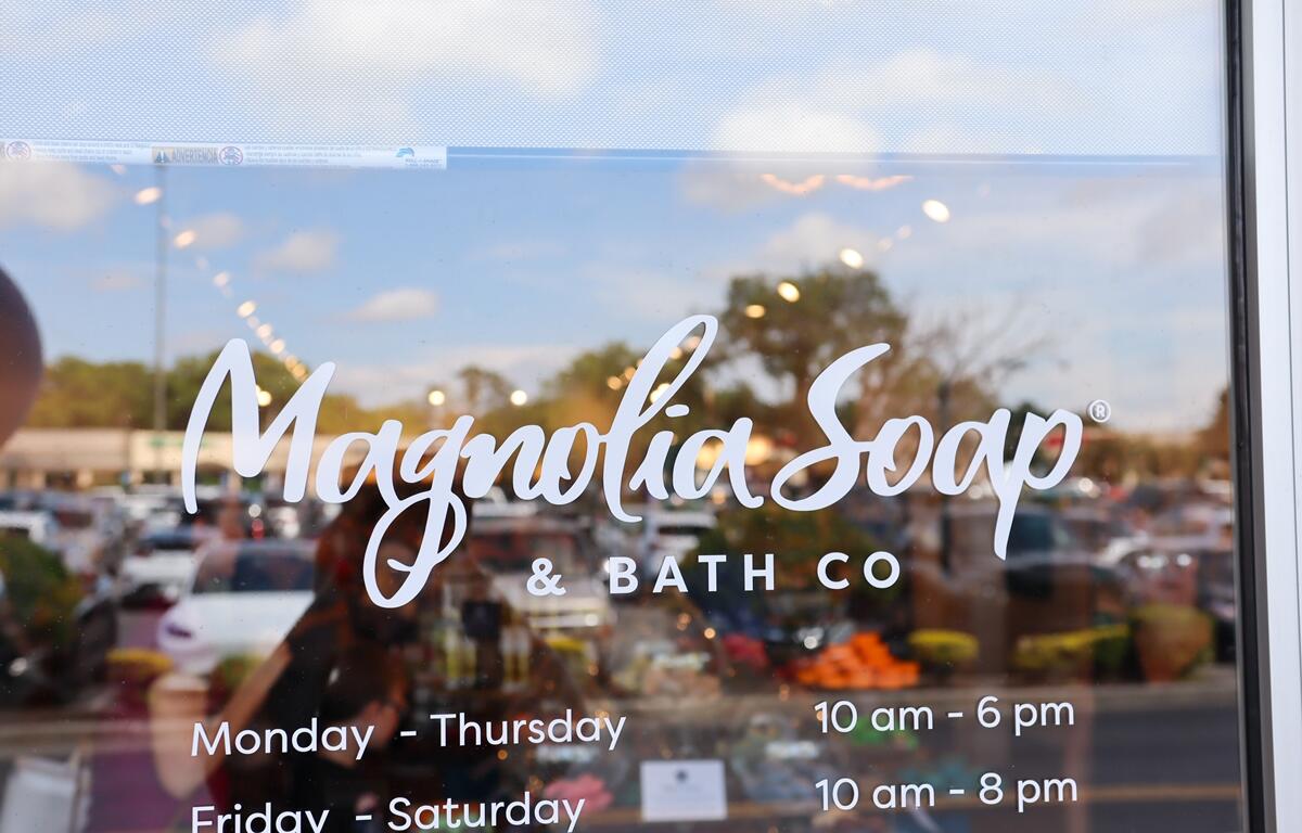 Magnolia Soap and Bath Company logo and business hours shown on the glass storefront window at Gaitway Plaza in Ocala.