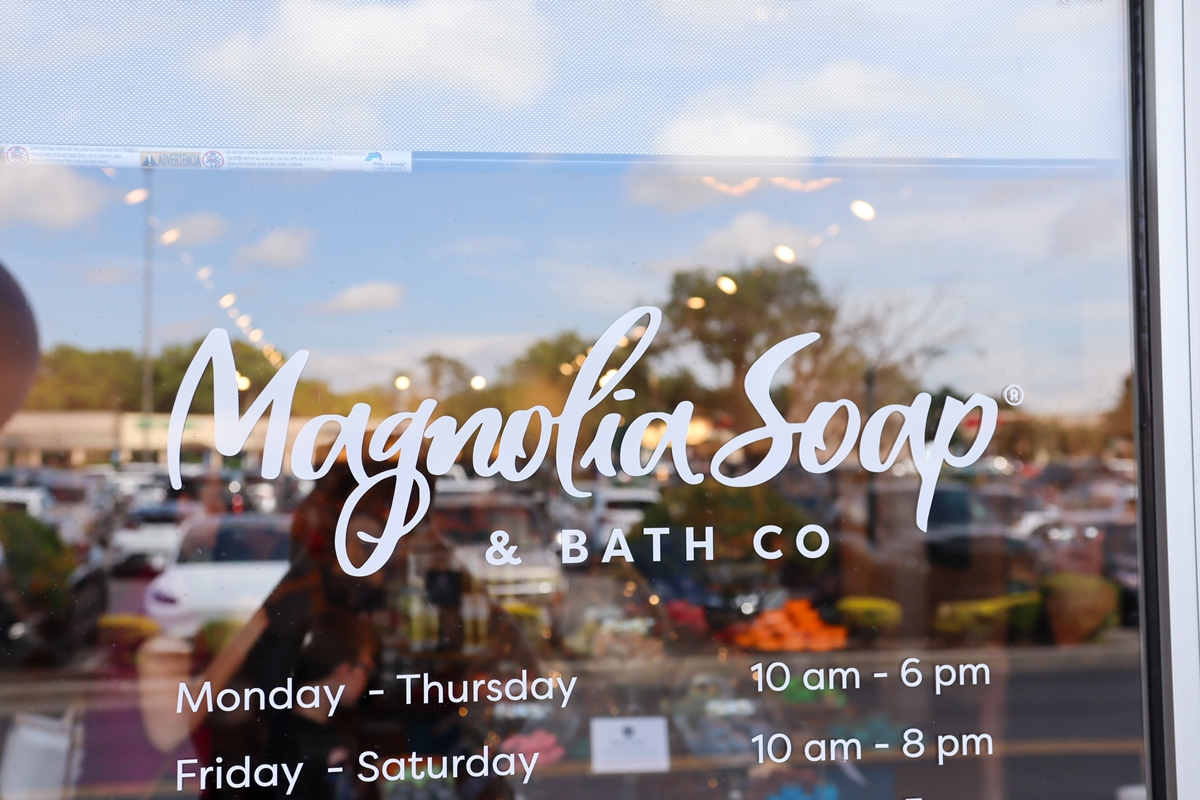 Magnolia Soap and Bath Company logo and business hours shown on the glass storefront window at Gaitway Plaza in Ocala.